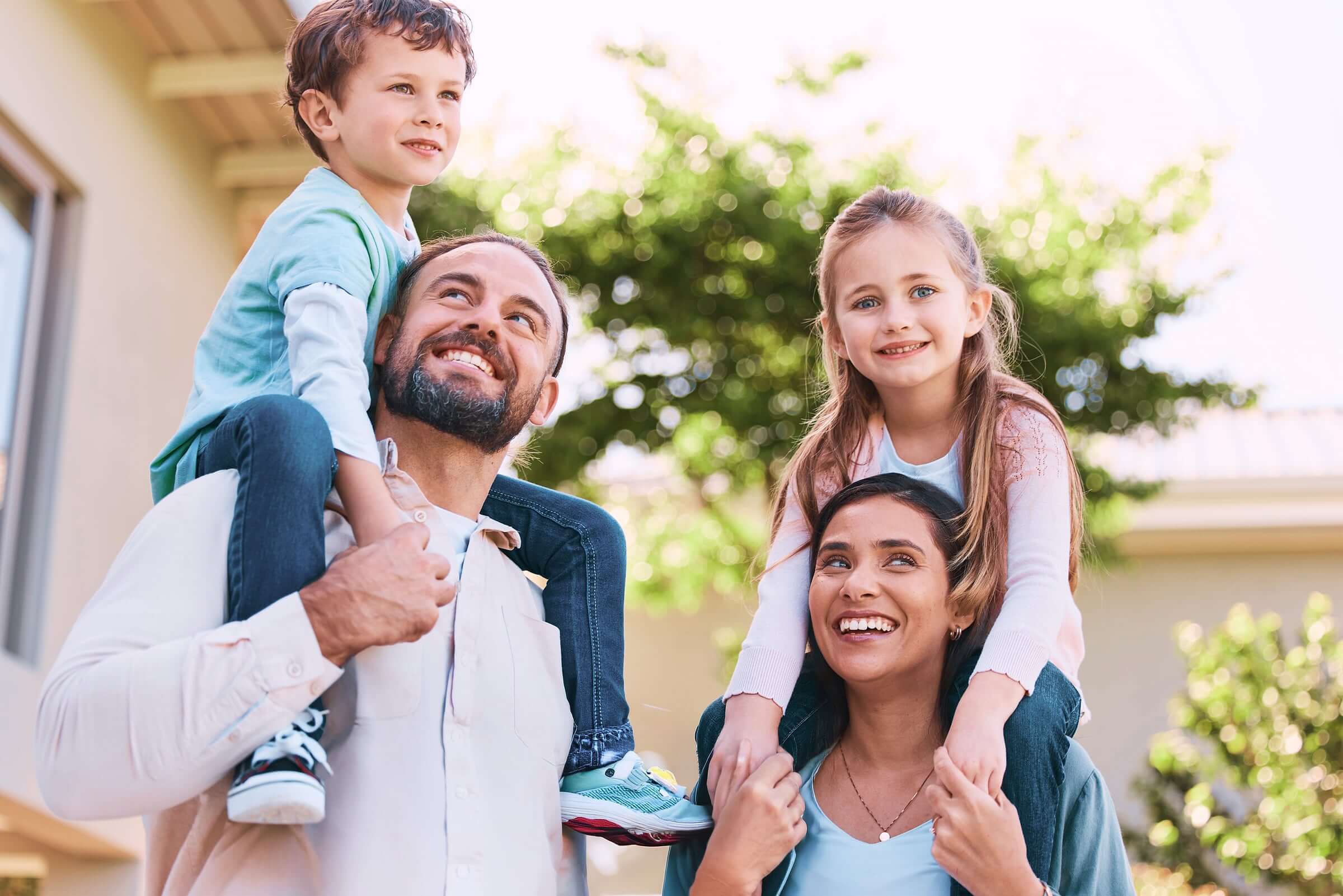 Happy family with kids on shoulders in front of their manufactured home